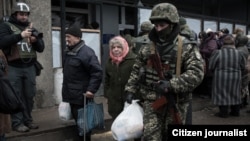 Раздача гуманитарной помощи в Дебальцево, начало февраля 2015 года. Военный помогает нести пакет пожилой женщине. К концу месяца город попал под оккупацию и остается захваченным доныне